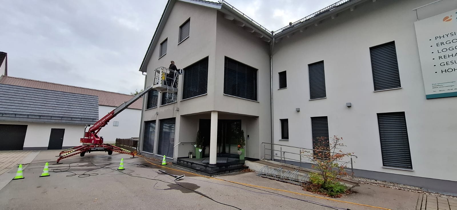 Großes Gebäude, dessen Fenster von einem Mitarbeiter mit einer Hebelbühne gereinigt werden